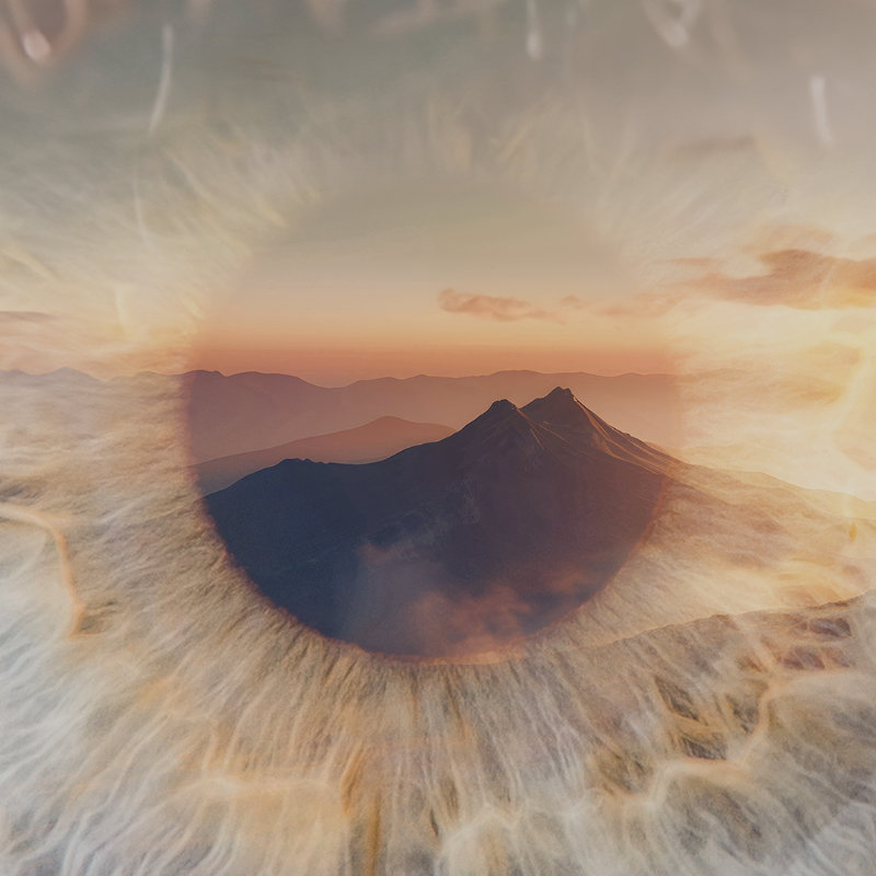 Doppelbelichtung einer menschlichen Iris, in deren Pupille eine Berglandschaft im warmen Abendlicht zu sehen ist.