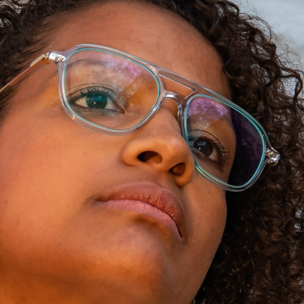 Eine Frau trägt eine transparente Brille mit einer Brillenglas-Randbeschichtung in der Farbe Teeblau.