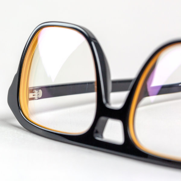 Eine Brille mit farbiger Brillenglas-Randbeschichtung liegt auf einem Tisch.