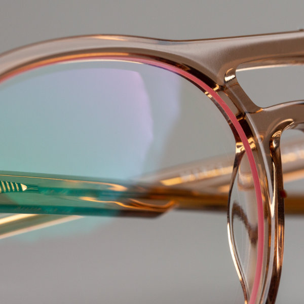 Nahaufnahme einer Brille mit Brillenglas-Randbeschichtung in einer ähnlichen Farbe wie die Brille selbst.